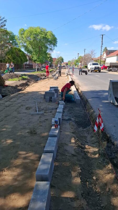 Szakember zsinór mentén fekteti a betonszegélyt az előkészített járdatükör szélén